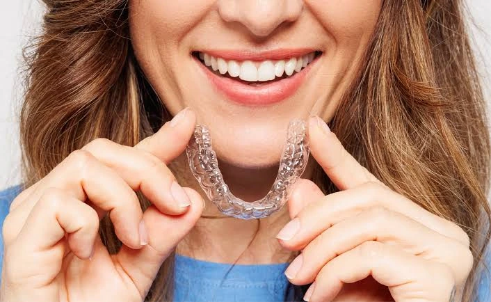 does invisalign hurt — woman holding a clear aligner tray comfortably